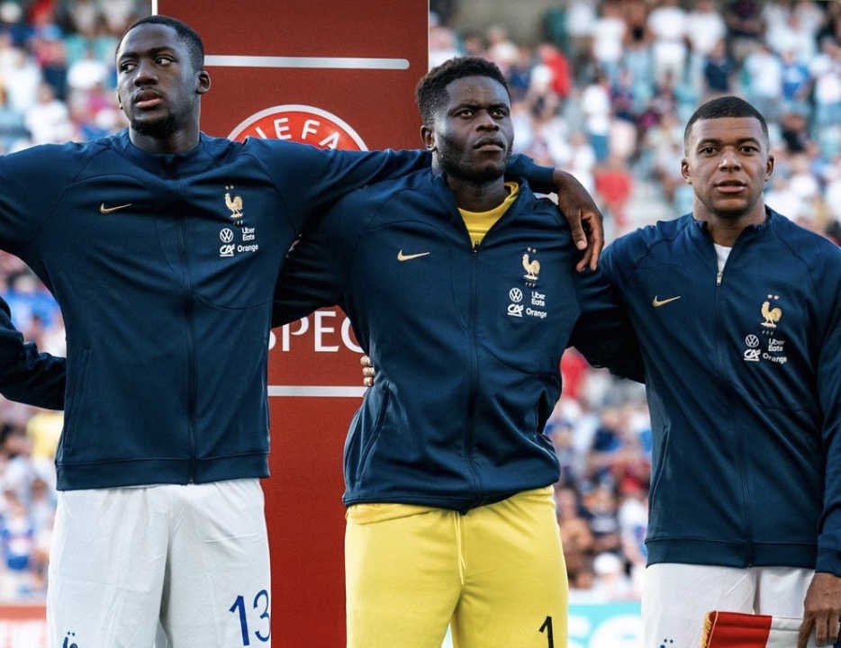 Brice Samba avant un match avec l’Équipe de France pendant l’hymne avec Konate et Mbappé
